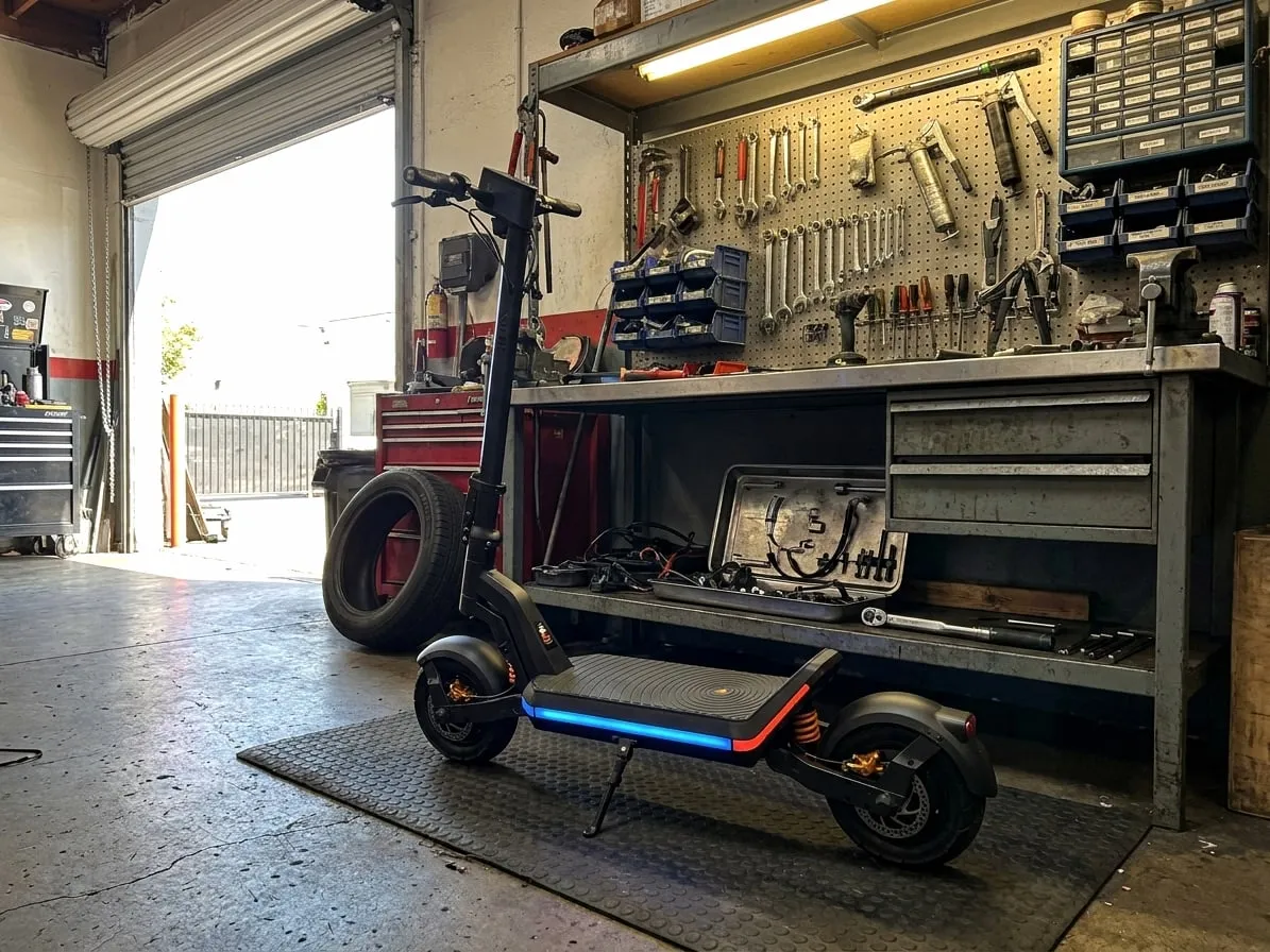 Apollo-style electric scooter with dual suspension standing in a repair workshop