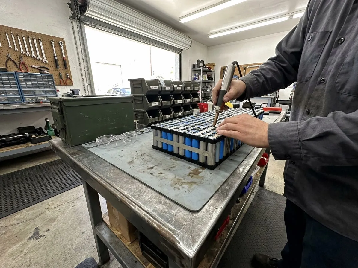 Technician spot-welding a nickel strip onto the cells of an opened electric scooter battery pack